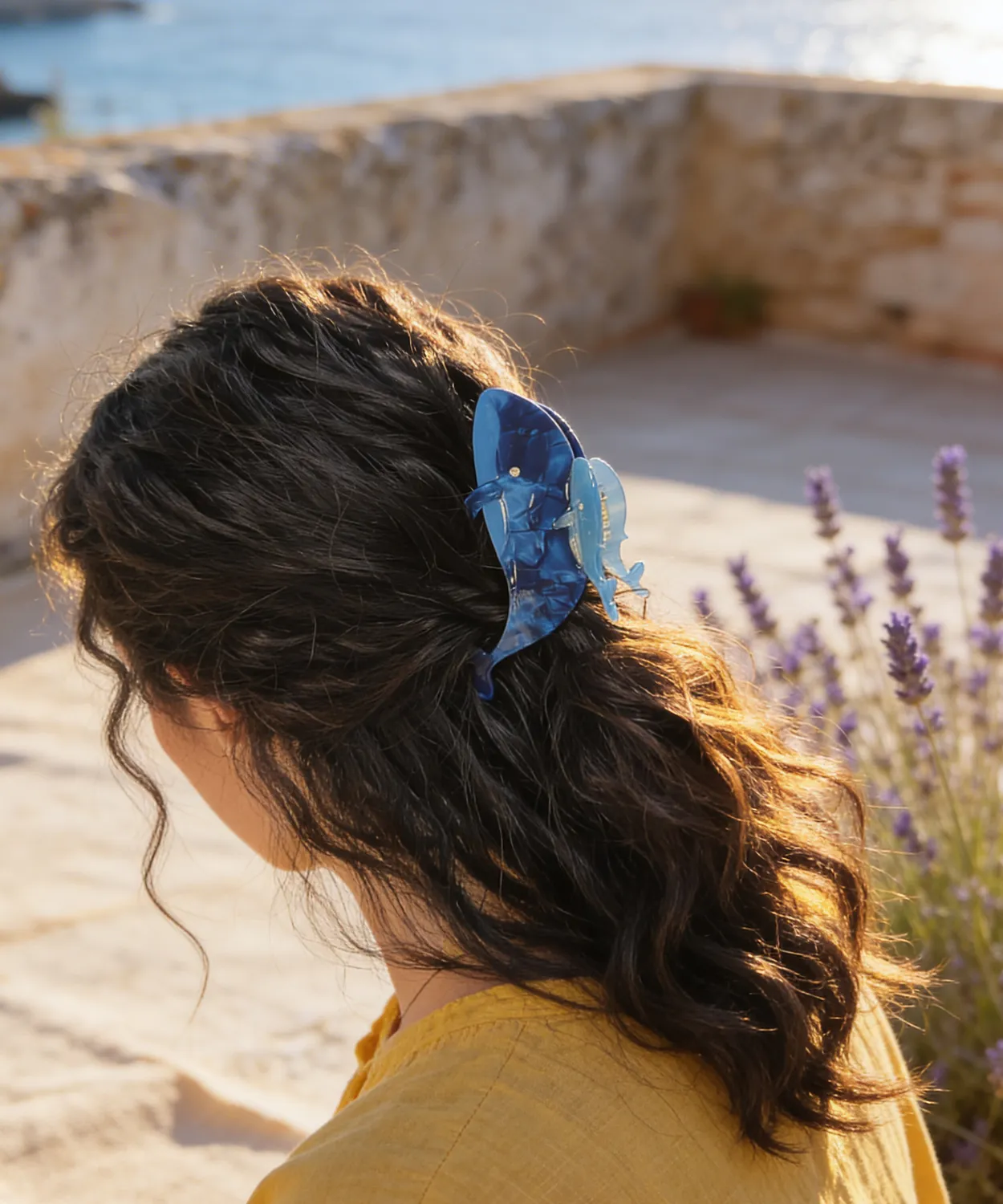 深淺藍雙鯨魚造型髮夾夾於女生捲髮，背面人像，薰衣草叢與地中海石牆背景