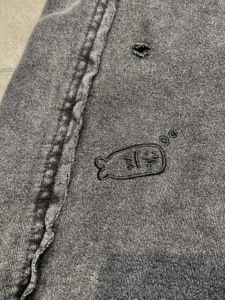 灰色重磅短褲布料特寫,展示鄭方瑜刺繡設計和褲側細節
