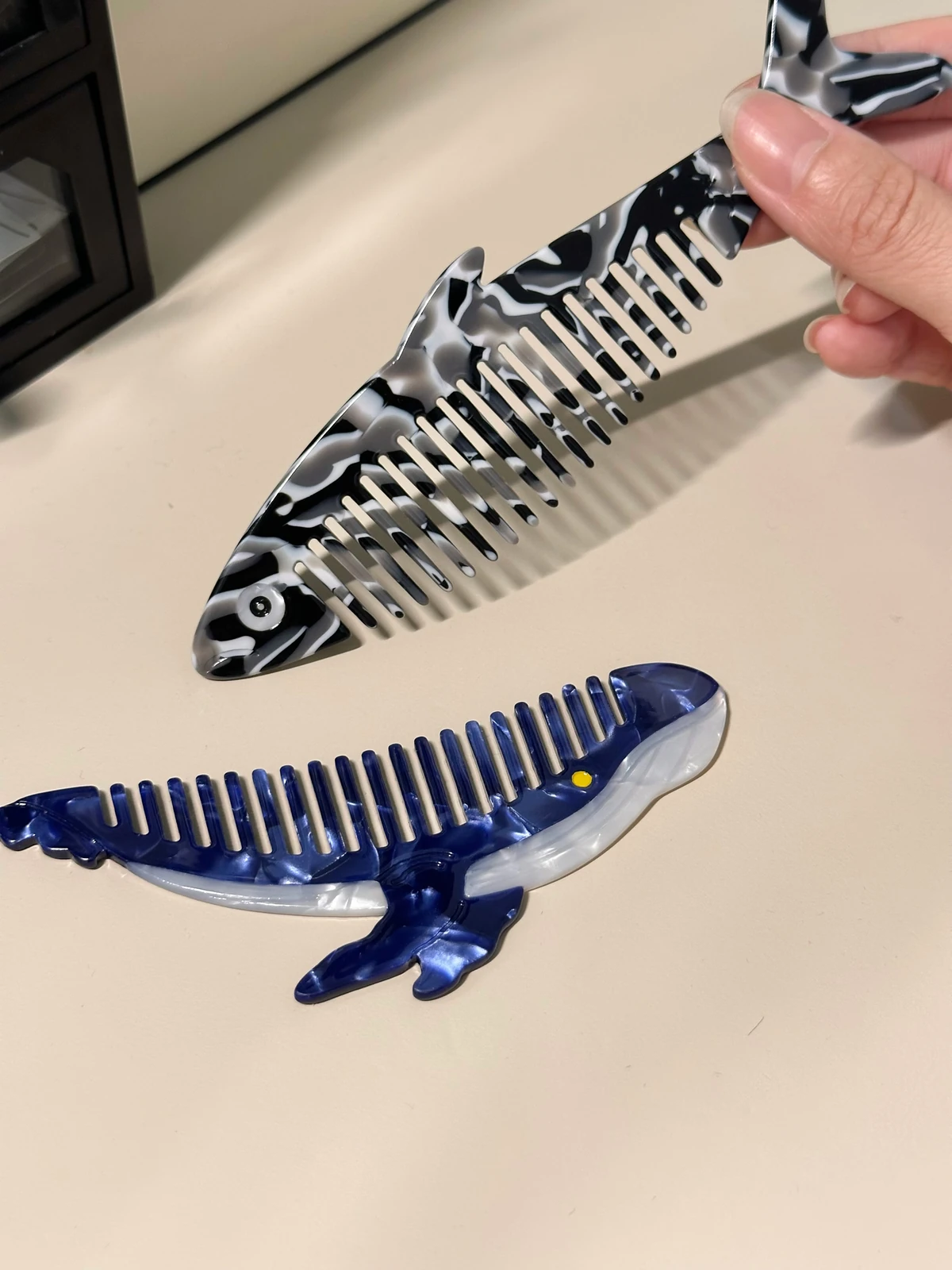 手拿黑色魚款深海順毛梳,下面是藍鯨款